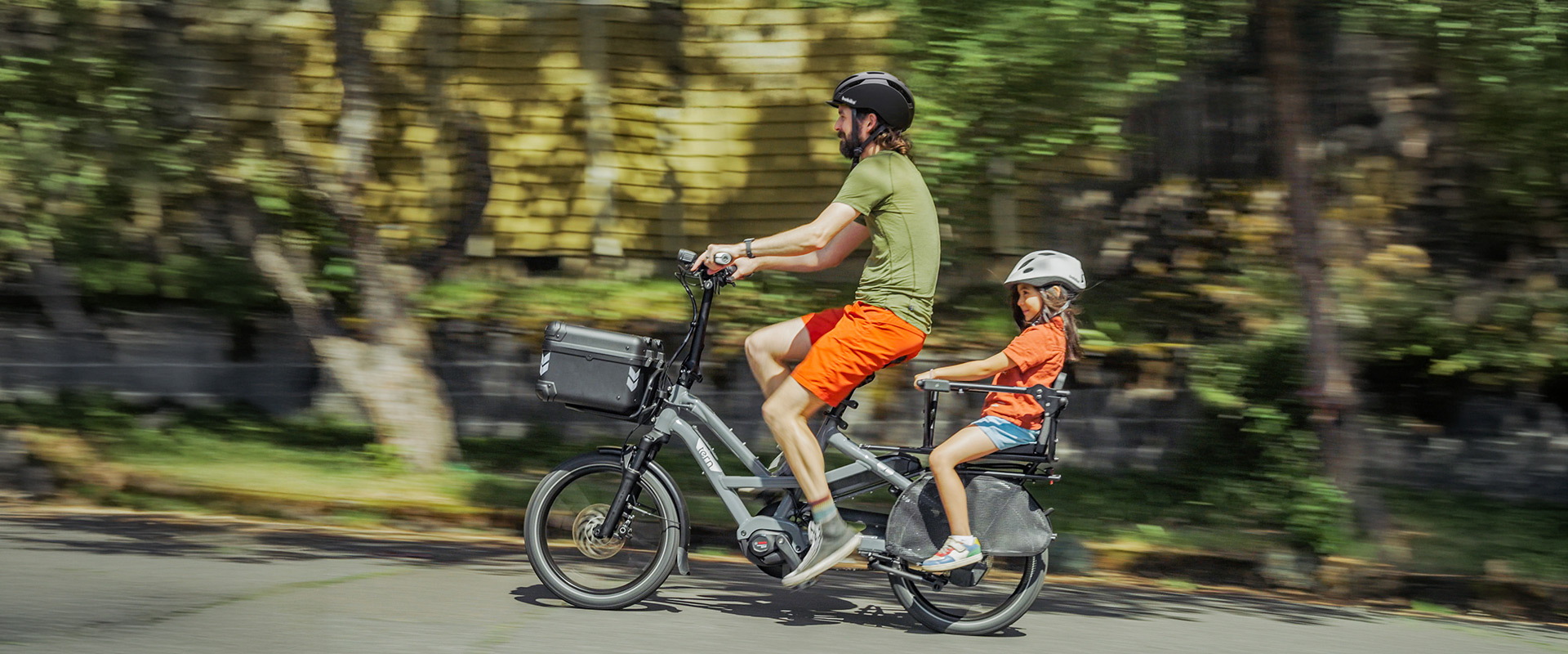 Un adulte et un enfant voyagent sur un vélo cargo