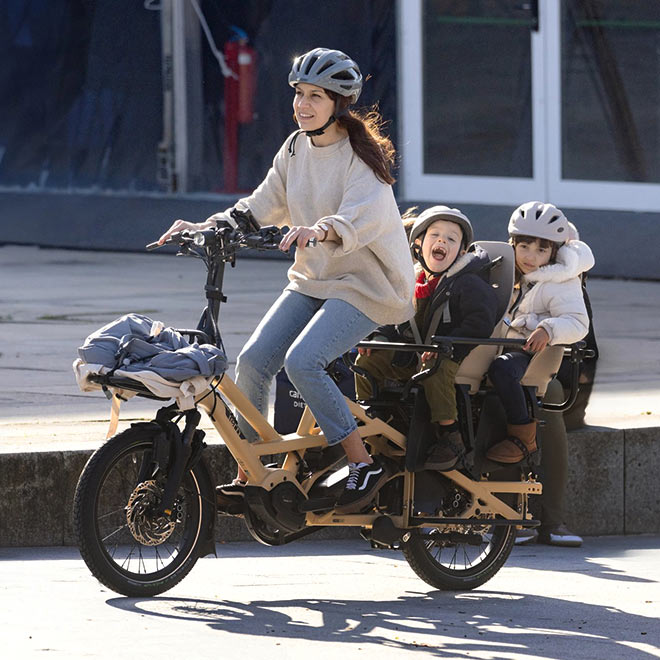 Une cycliste transporte deux enfants sur un vélo cargo Tern