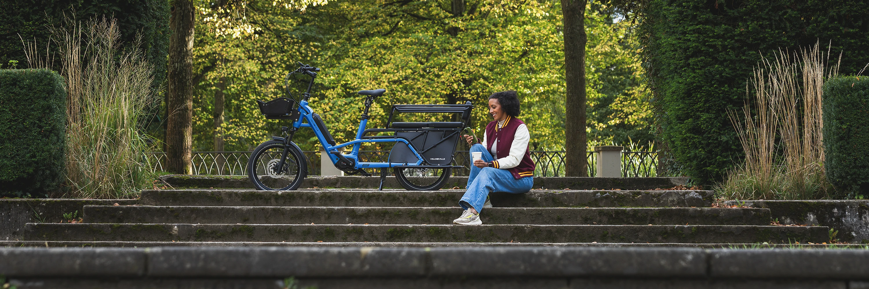 Vélo cargo Loady bleu et cycliste dans un parc